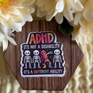 May include: A rectangular sticker with a black background featuring the text ADHD IT'S NOT A DISABILITY IT'S A DIFFERENT ABILITY in colorful lettering. The design includes four white skeleton figures, with the third one in a vibrant rainbow gradient.