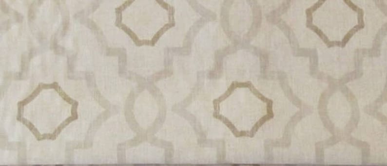 May include: A white fabric with a beige geometric pattern. The pattern is made up of repeating octagons and lines.