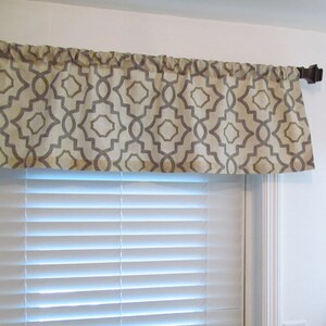 May include: A beige and gray geometric patterned valance with a brown curtain rod.