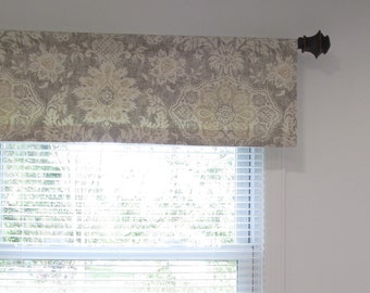 May include: A beige and brown patterned valance with a decorative finial on the rod.