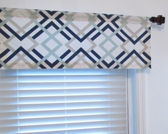May include: A white valance with a geometric pattern in shades of blue and gray. The valance is hung on a brown curtain rod.