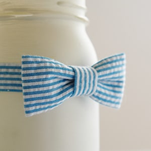 May include: A white jar with a blue and white striped bow tied around it.
