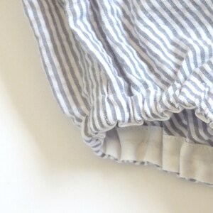 May include: Gray and white striped fabric with a white elastic band at the bottom.
