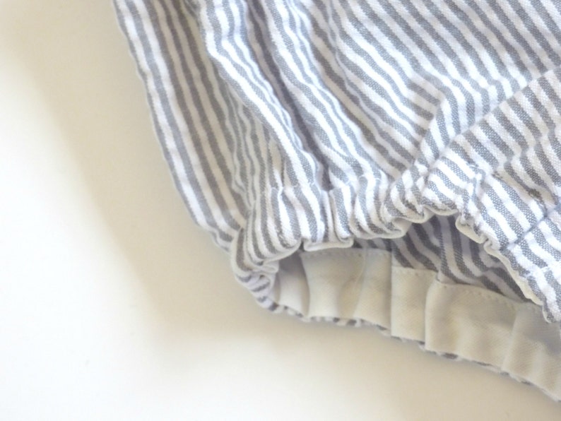 May include: Gray and white striped fabric with a white elastic band at the bottom.