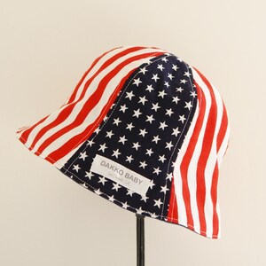 Baby summer hat, shaped like a bucket with an American flag pattern.  Red and white stripe on the side and white star on navy in the middle. The name label on it said DAKKO BABY.