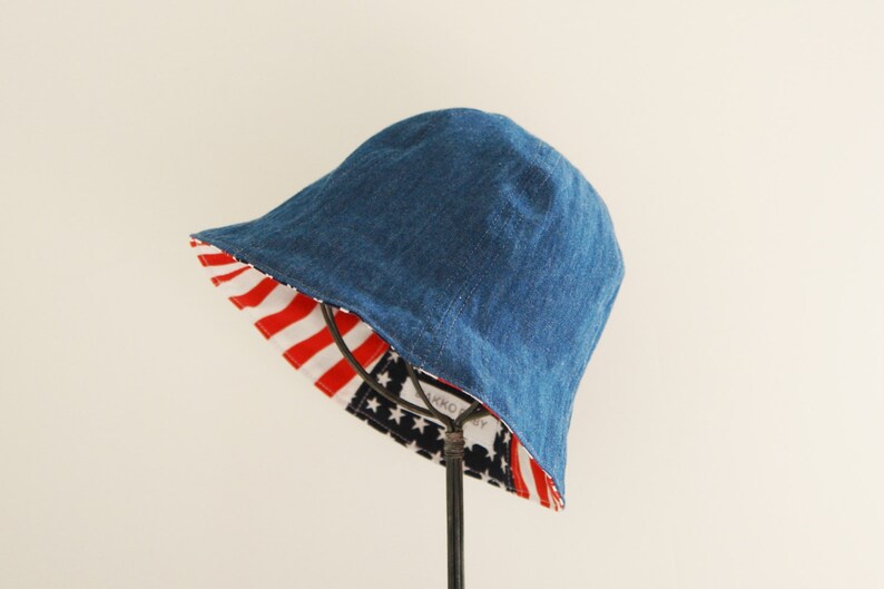 May include: A blue denim bucket hat with a red, white, and blue American flag print on the inside.