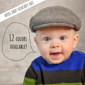 May include: A gray wool newsboy hat on a baby. The baby is wearing a blue, green, and gray striped sweater. Text in a speech bubble says "12 COLORS AVAILABLE!"