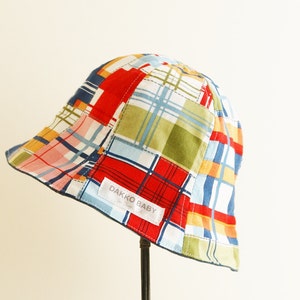 May include: A colorful patchwork baby hat with a blue brim and a white label that says "Dakko Baby".