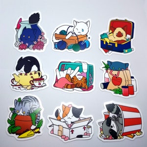 May include: Set of ten colorful stickers featuring cats in various poses and settings. The stickers are printed on white paper with a glossy finish. The stickers feature cats in a variety of settings, including a tea party, a box, a basket of yarn, a suitcase, and a cat carrier.