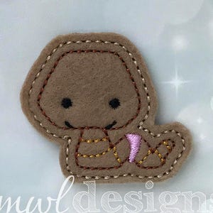 May include: A brown felt applique of a snake with a pink tail. The snake has a simple face with black eyes and a stitched smile.