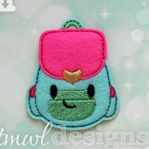 May include: A turquoise blue felt backpack with a pink felt flap, a gold heart, and a green felt pocket. The backpack has a smiling face with black eyes.