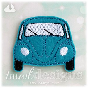 May include: A teal blue felt applique of a vintage Volkswagen Beetle car with white headlights and windshield wipers. The car is outlined in black thread.