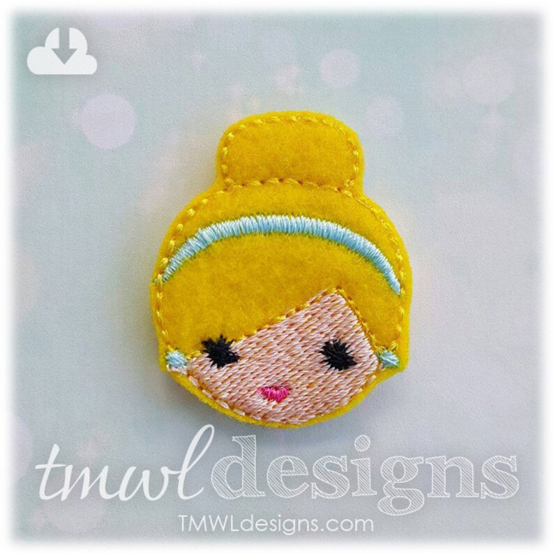 May include: A felt appliqu&eacute; of a cartoon princess with blonde hair, a blue headband, and a pink face. The appliqu&eacute; is yellow and has embroidered details.
