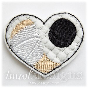 May include: A white felt heart-shaped patch with a basketball design on one side and a black circle on the other side. The basketball design is in white and gold thread. The black circle is outlined in black thread.