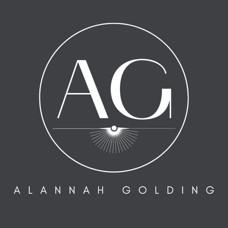 May include: A logo design featuring the white letters "AG" inside a white circle, set against a dark gray background. Below the circle, the text "ALANNAH GOLDING" is displayed in white. The design includes a stylized sunburst element.
