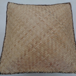 May include: A square woven cushion with a natural beige colour and a black stitched border.