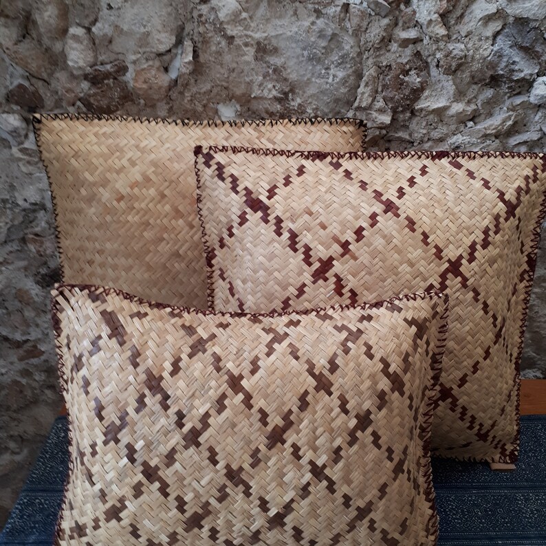 May include: Three woven cushions with brown and beige patterns and brown stitching. The cushions are stacked on top of each other.