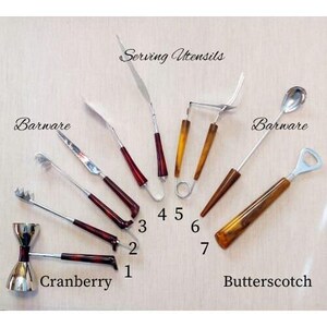 Peut inclure: Un ensemble de dix ustensiles de bar et de service avec des manches marbrés brun et rouge. Les ustensiles comprennent un ouvre-bouteille, un shaker à cocktail, une cuillère, une fourchette, une passoire et une pince. Le texte "Serving Utensils", "Barware", "Cranberry", "Butterscotch" est visible sur l'image.