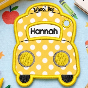 Può includere: Una toppa a forma di scuolabus giallo con pois bianchi, due fari gialli e un cartello rettangolare bianco con il testo nero Hannah. La parte superiore della toppa mostra il testo nero School Bus. La toppa presenta un bordo di colore giallo.