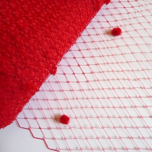 May include: Red tulle fabric with a diamond pattern and small red pom-poms.