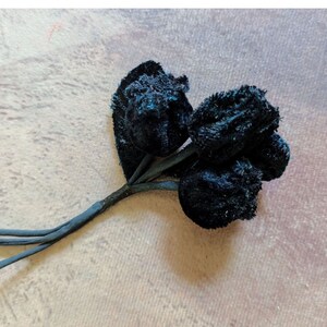 May include: A bouquet of three black velvet roses with stems.