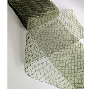 May include: Olive green decorative ribbon with a diamond pattern. The ribbon is rolled up, with a portion unrolled, showing the intricate mesh design. The ribbon is made of a soft, textured material.