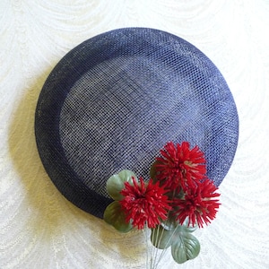 May include: A navy blue mesh hat with a round shape and a cluster of red silk flowers.