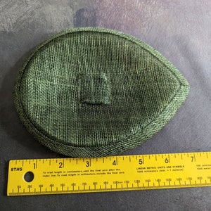 May include: A green oval-shaped hat made of a woven material. The hat is approximately 5 inches in diameter.