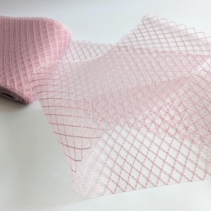May include: Pink tulle fabric with a diamond pattern. The tulle is soft and sheer, and the diamond pattern is delicate and intricate.