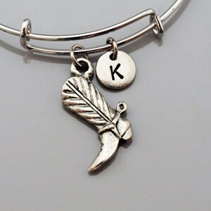 May include: Silver charm bracelet with a boot charm and a letter K charm.
