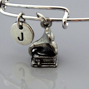 May include: A silver charm bracelet with a letter J charm and a vintage gramophone charm.