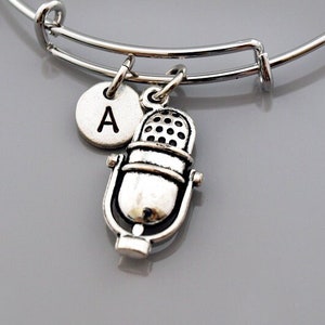 May include: Silver charm bracelet with a microphone charm and a letter A charm. The bracelet is expandable and has a silver finish.