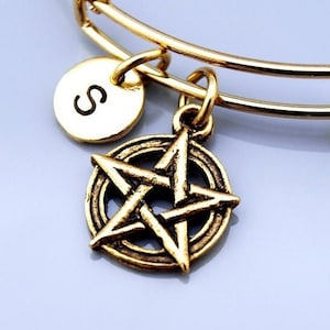 May include: Gold charm bracelet with a pentagram charm and a personalized disc charm with the letter "S".