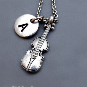 Può includere: Una collana d'argento con un ciondolo a forma di violino e un ciondolo rotondo con la lettera A.