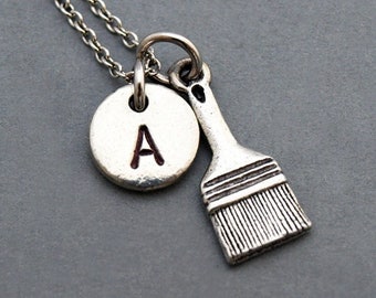 Può includere: Collana d'argento con un ciondolo a forma di pennello e un ciondolo rotondo con la lettera A.