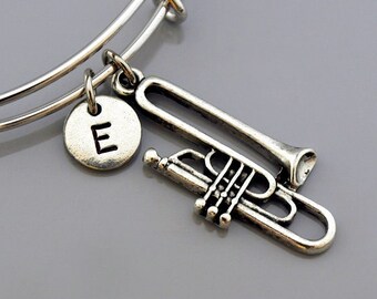 May include: Silver charm bracelet with a trumpet charm and a silver charm with the letter E.