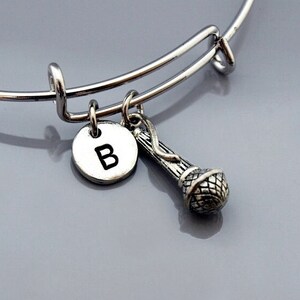 May include: A silver charm bracelet with a microphone charm and a silver charm with the letter B.