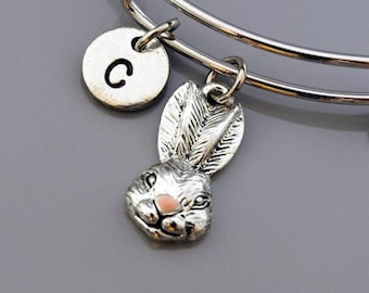 Könnte beinhalten: Silbernes Charm-Armband mit einem Hasen-Anhänger und einem Buchstaben 'C'-Anhänger. Das Armband ist erweiterbar und hat eine silberne Oberfläche.