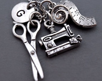 May include: Silver necklace with a sewing machine charm, a measuring tape charm, a pair of scissors charm, and a personalised initial charm.