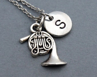 Puede incluir: Collar de plata con un dije de trompa francesa y un dije inicial de plata con la letra 'S'.