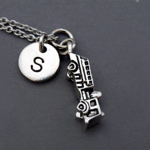 May include: Silver necklace featuring a fire engine charm and a round charm with the letter "S" engraved on it.