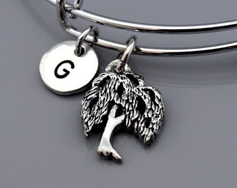 May include: A silver charm bracelet featuring a tree charm and a charm with the letter G. The bracelet is expandable and has a silver finish.