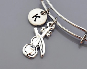 May include: A silver expandable bangle bracelet with a silver charm of a violin and a silver charm with the letter K.