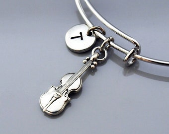 May include: A silver charm bracelet with a silver violin charm and a silver charm with the letter T.
