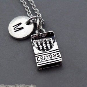 May include: A silver necklace with a silver charm that says "CRAYONS" and a silver charm with the letter "M".