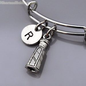 May include: A silver charm bracelet with a silver charm in the shape of a salt shaker and a silver charm with the letter R.