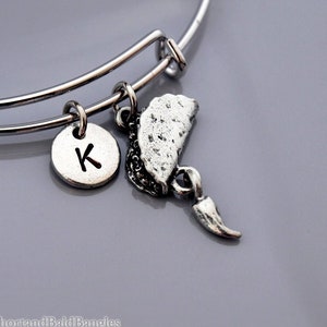 Pode incluir: Pulseira de prata com um berloque de prata com a letra K, um berloque de prata de taco e um berloque de prata de pimenta.