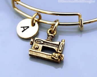 Op de afbeelding: Gouden armband met een gouden letter A-bedel en een gouden naaimachine-bedel.