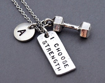 May include: Silver necklace with a dumbbell charm, a tag that says "I Choose Strength", and a round charm with the letter "A".
