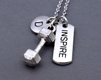 May include: Silver necklace with a dumbbell charm, a round charm with the letter "D" and a rectangular tag with the word "INSPIRE" engraved on it.